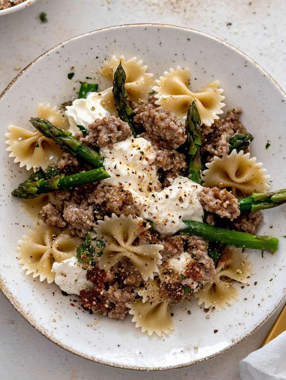 A bowl of food with pasta, sausage, and asparagus recipe.