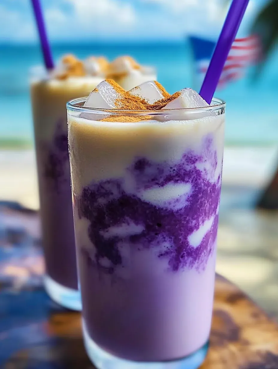 A glass of purple drink with ice and a straw.