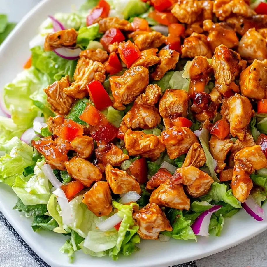 Chicken salad piled on a plate with juicy lettuce and ripe tomatoes.
