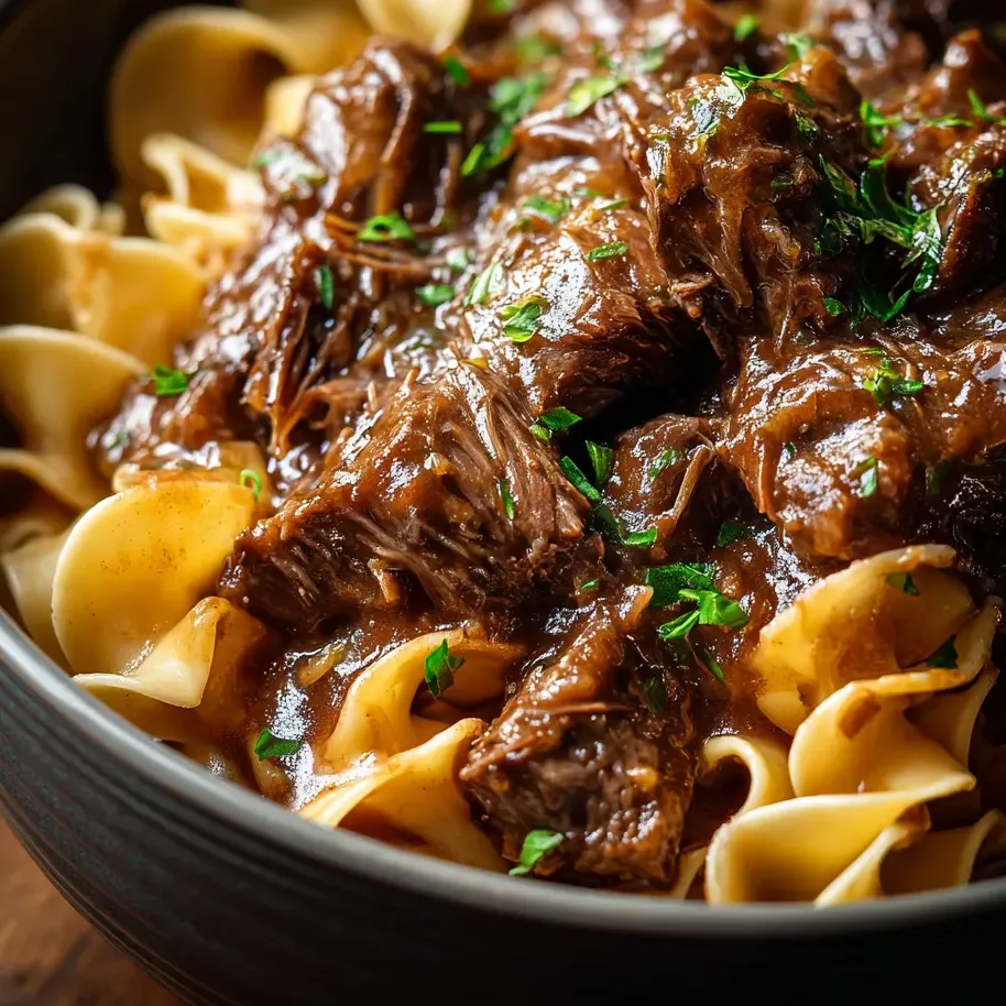 A bowl loaded with noodles, saucy beef, and rich broth.