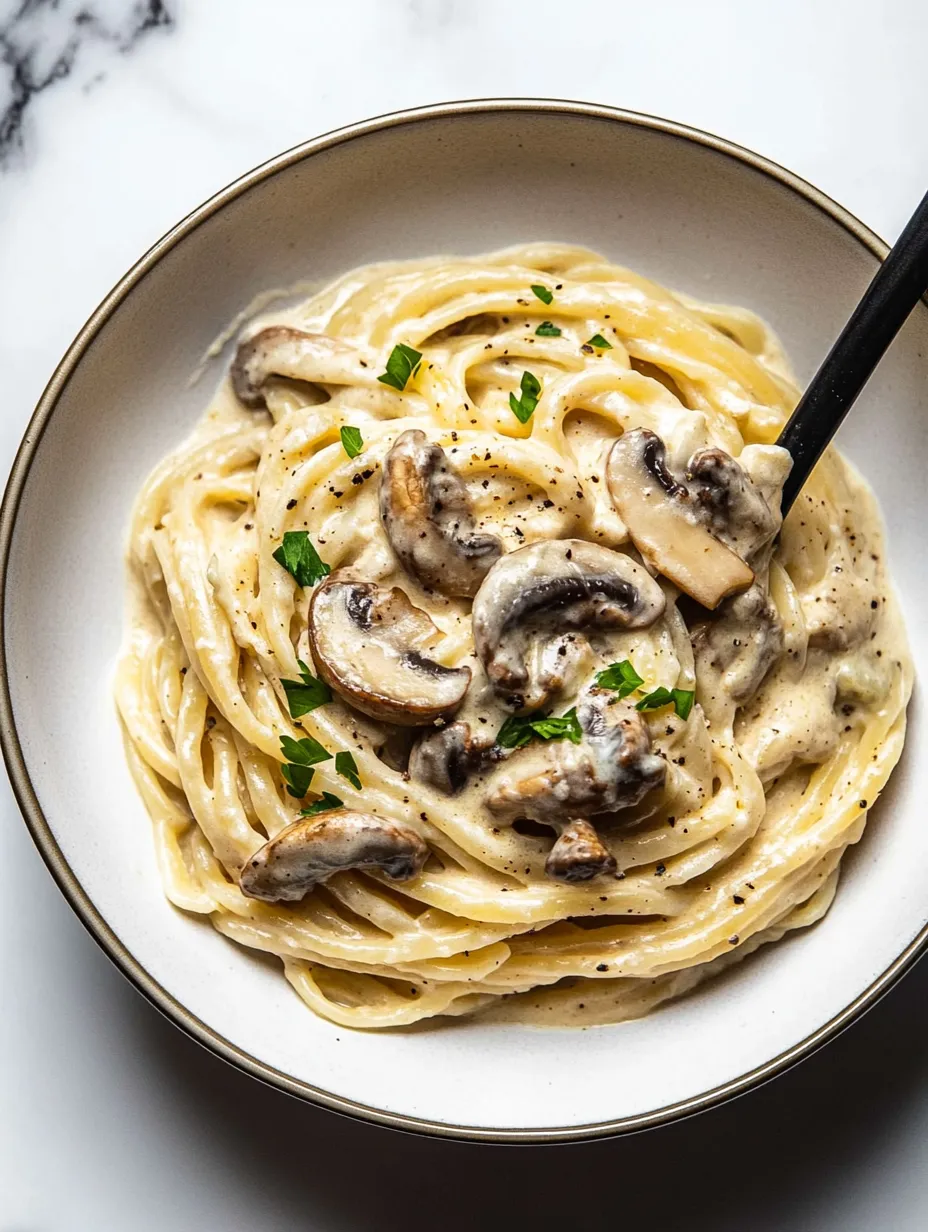 A bowl of pasta with mushrooms and herbs.