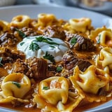 A plate of food with a cheesy beef enchilada tortellini.