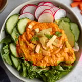A bowl of salad with cucumbers, radishes, and carrots.