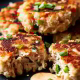 A plate of tuna cakes with mayo on it.
