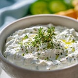 A bowl of dip topped with parsley leaves.