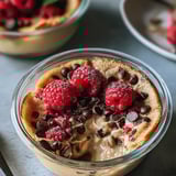 A bowl with raspberries and chocolate chips on top.