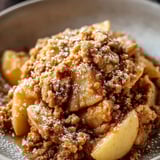 A bowl filled with oats and apple, spoon inside.