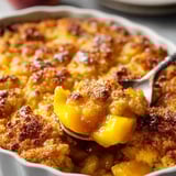 A spoon scooping out moist peach cobbler.