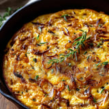 A pan full of onions and scattered herbs, fresh and ready to eat.