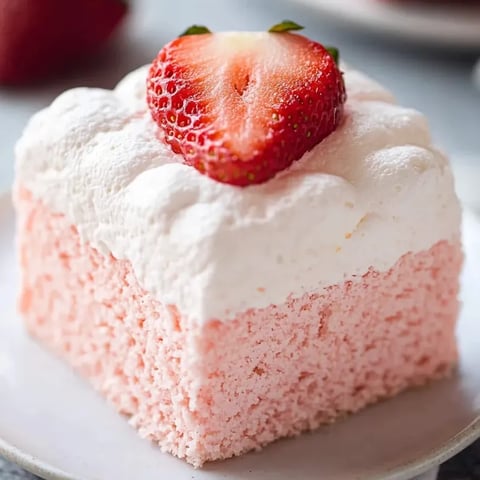Pink and white cake slice, topped with a strawberry.