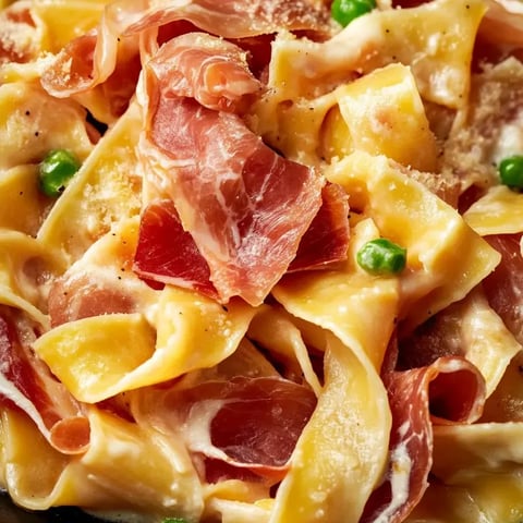 A plate of pasta with ham and peas.