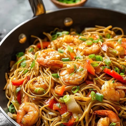 A bowl filled with shrimp, noodles, and veggies.