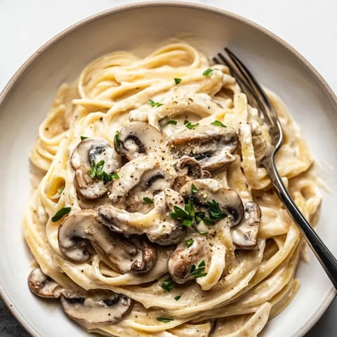 A bowl filled with mushroom pasta sprinkled with herbs.