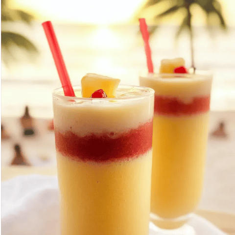 Two glasses of pineapple juice with red straws.