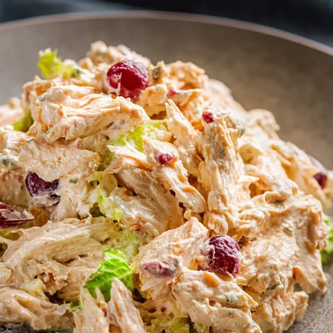 Big plate covered with salad and chicken chunks.