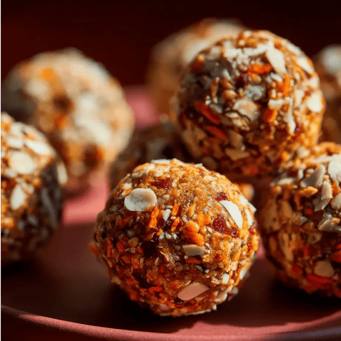 Carrot cake snack balls in a bowl with nuts and raisins.